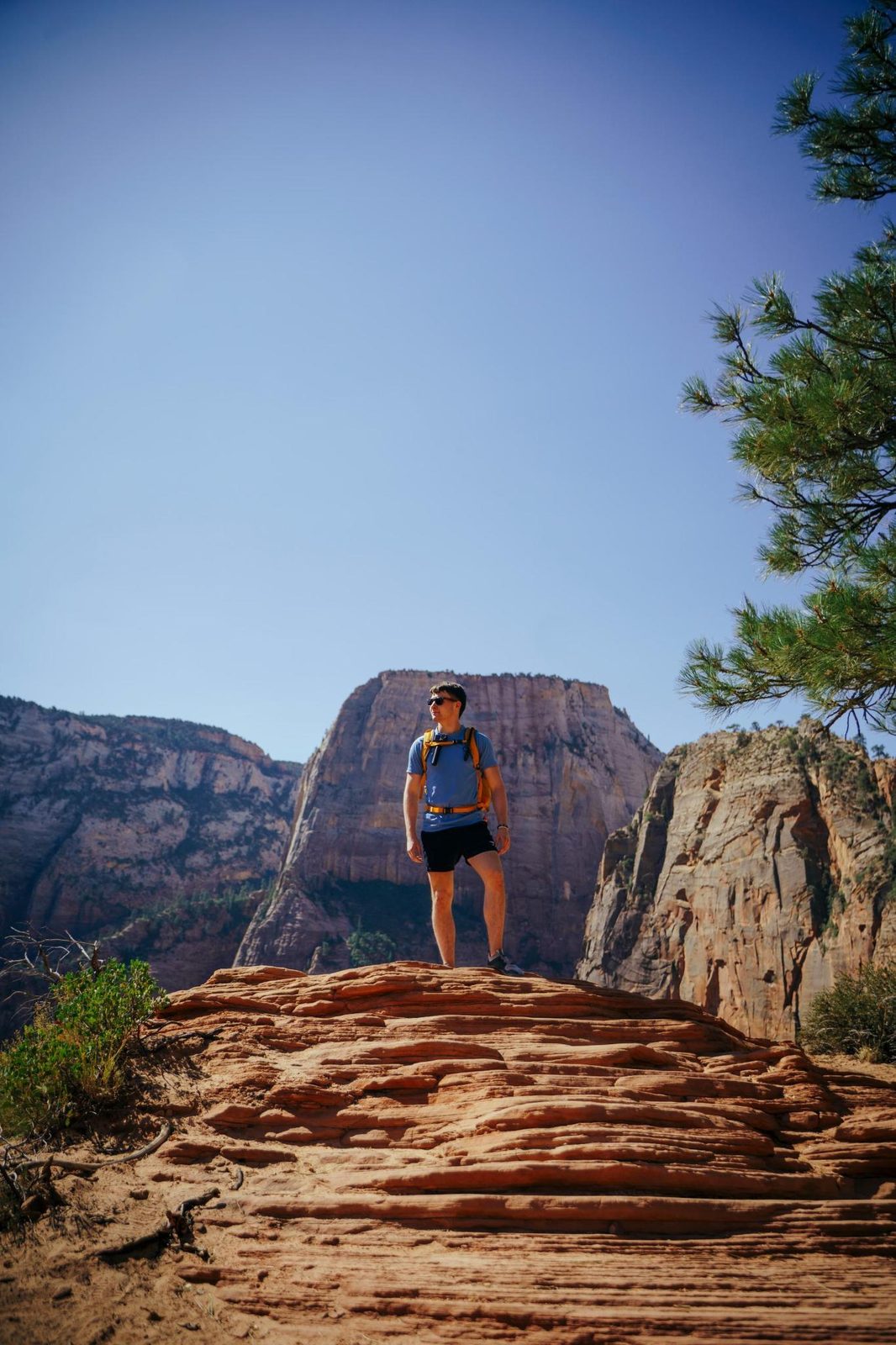 Duncan Bannon standing on red sandstone with the cliffs of Zion National Park behind.